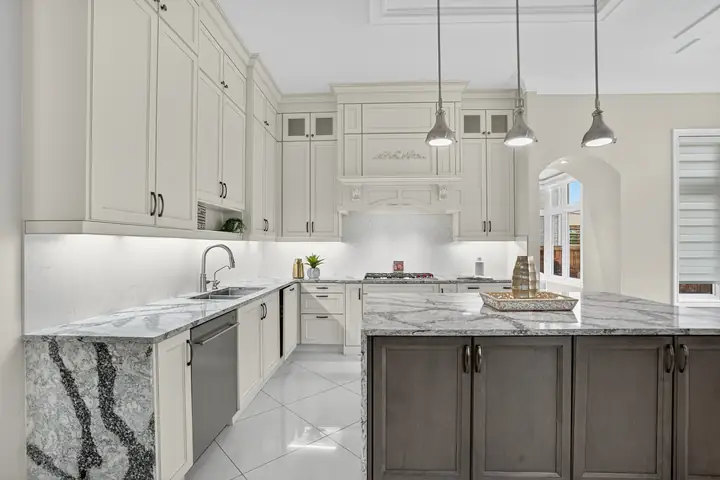 White kitchen with a marble island and pendants