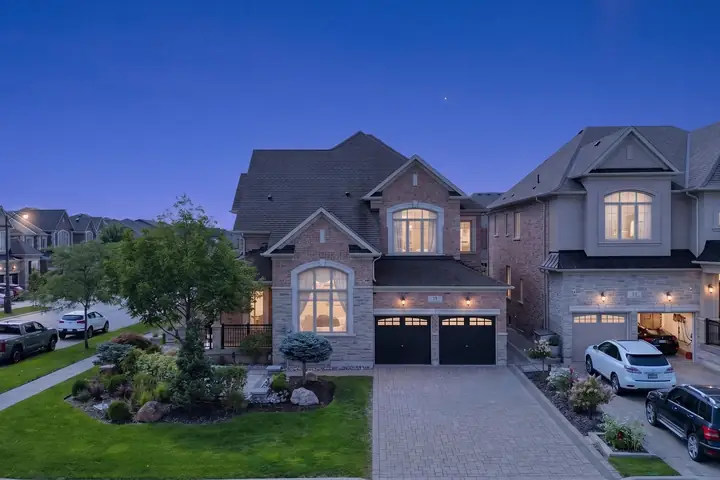 Two detached homes with lit garages at dusk
